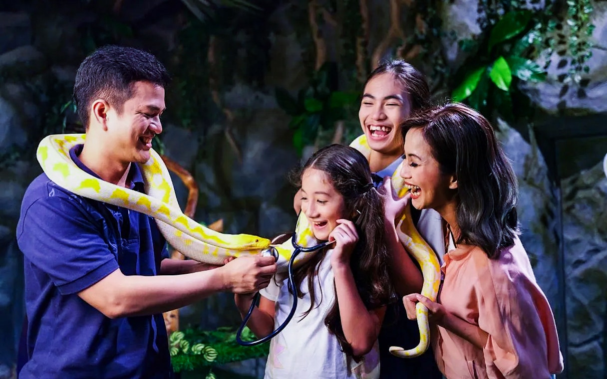 Tourists interacting with a snake at Jakarta Aquarium Safari.
