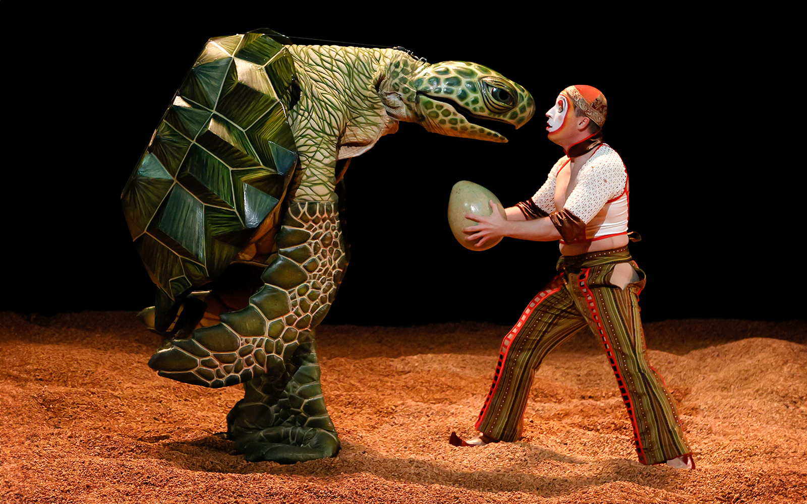 Performer with turtle puppet in Cirque du Soleil KÀ show.