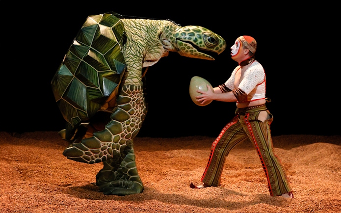 Performer with turtle puppet in Cirque du Soleil KÀ show.