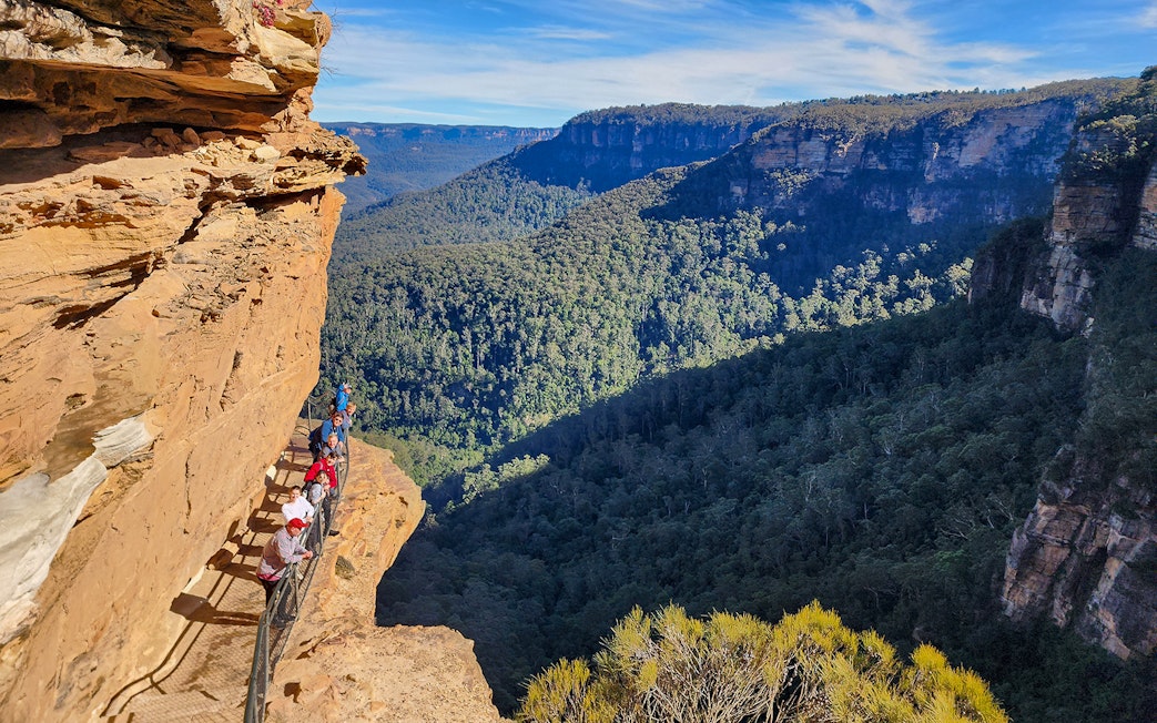 Tour group walking along a cliffside trail in the Blue Mountains, Australia.