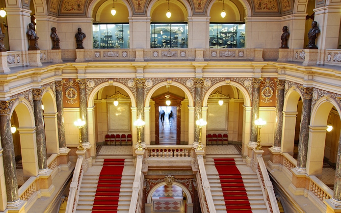 Grand staircase inside the National Museum, Prague, with ornate arches and statues.