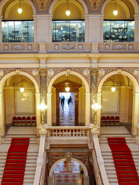Grand staircase inside the National Museum, Prague, with ornate arches and statues.