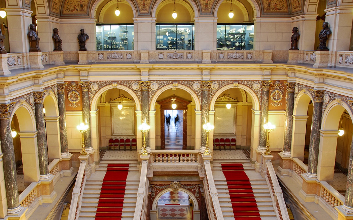 Grand staircase inside the National Museum, Prague, with ornate arches and statues.