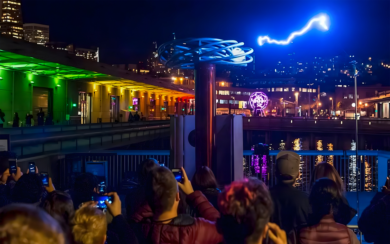 Crowd watching a light display at night outside the Exploratorium in San Francisco.