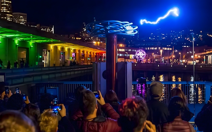 Crowd watching a light display at night outside the Exploratorium in San Francisco.