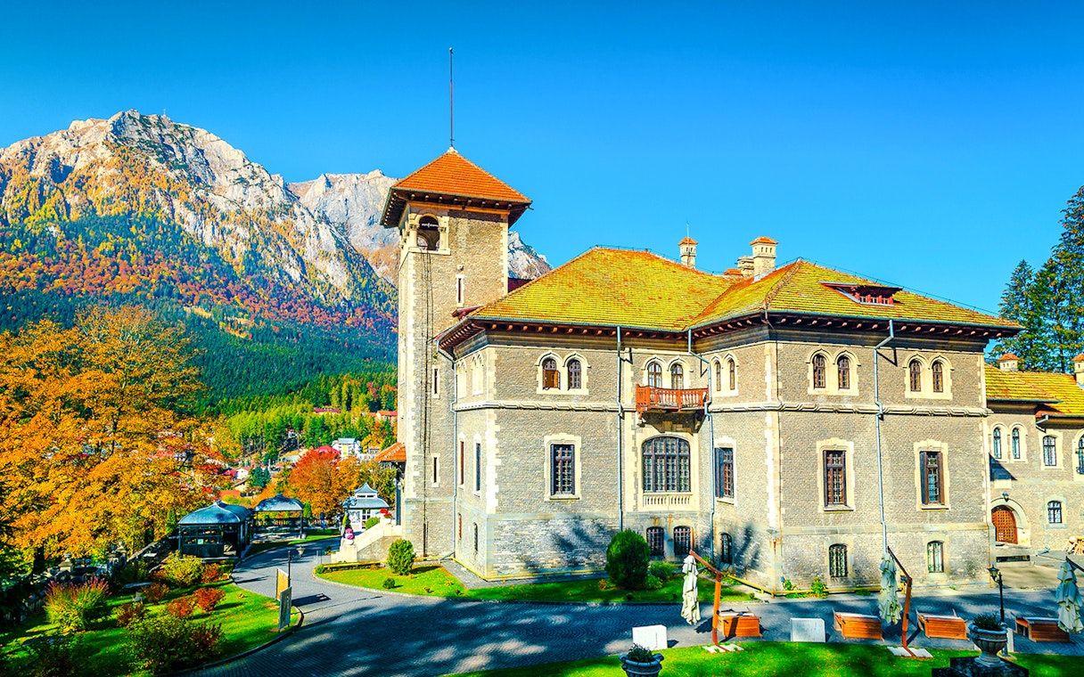 Cantacuzino Castle with garden and mountain backdrop, Romania, Europe.