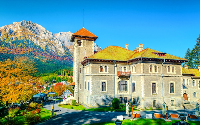 Cantacuzino Castle with garden and mountain backdrop, Romania, Europe.