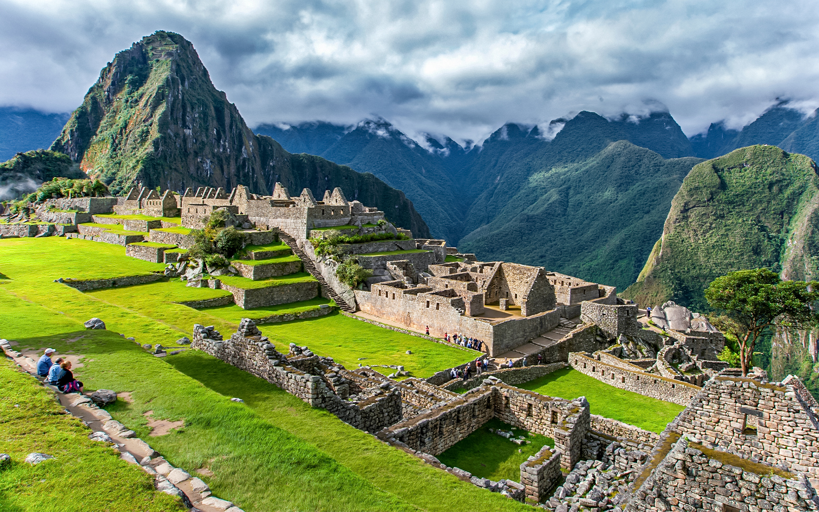 Machu Picchu ruins with terraces and Huayna Picchu mountain in the background.