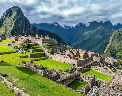 Machu Picchu ruins with terraces and Huayna Picchu mountain in the background.