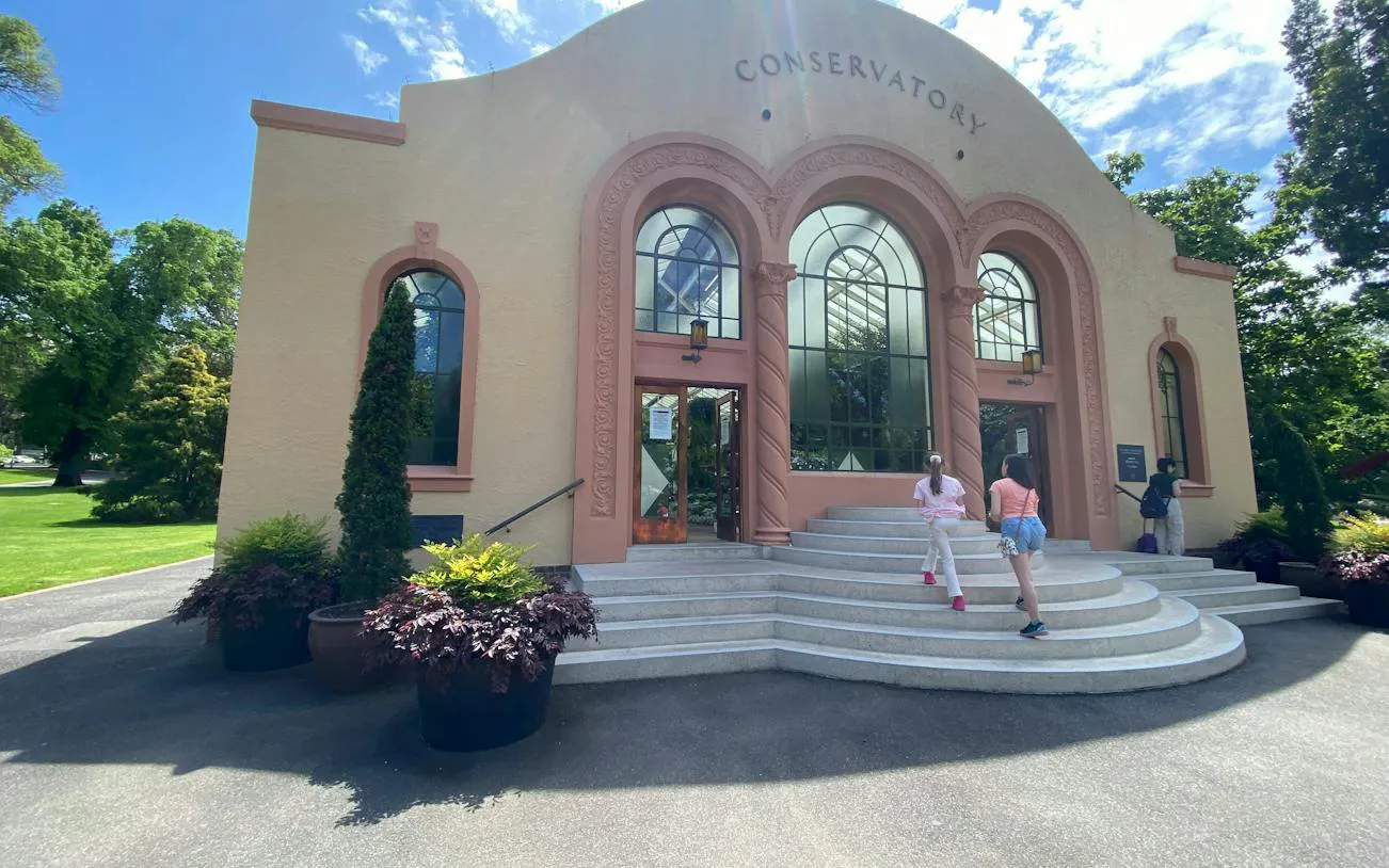 Conservatory entrance at Fitzroy Gardens, Melbourne, with visitors ascending steps.