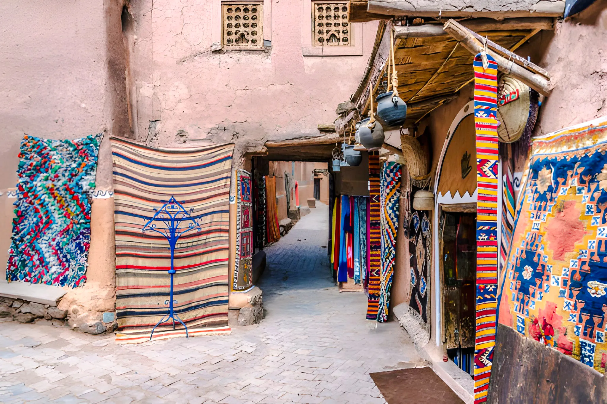 Colorful rugs and pottery in a narrow alley of Marrakesh souk, showcasing local artisan crafts.
