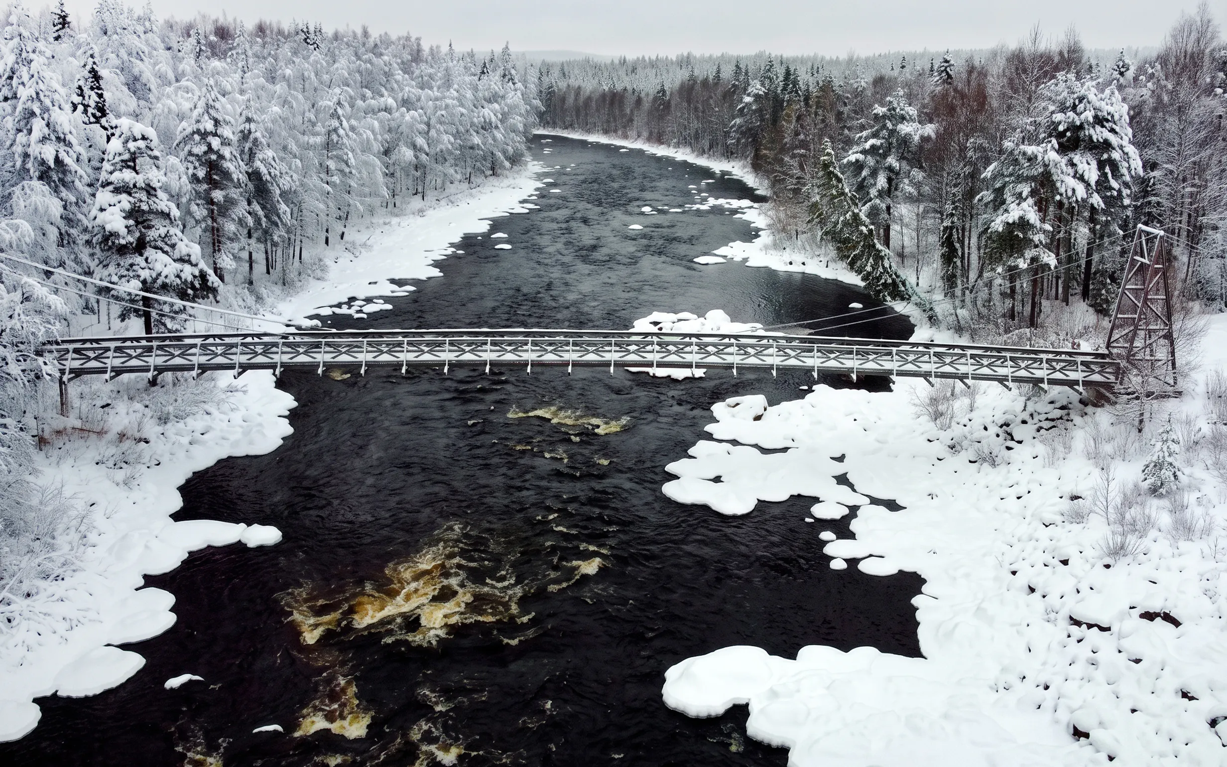 Bridge over snowy river in Vikakongas Nature Reserve, Rovaniemi.
