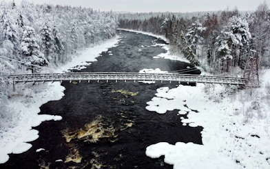 Bridge over snowy river in Vikakongas Nature Reserve, Rovaniemi.