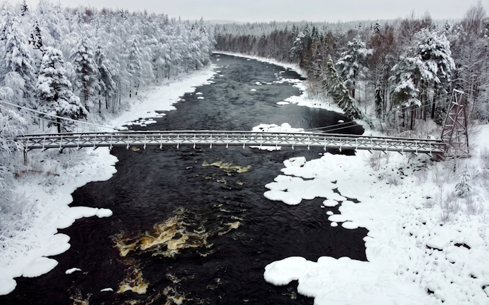 Bridge over snowy river in Vikakongas Nature Reserve, Rovaniemi.