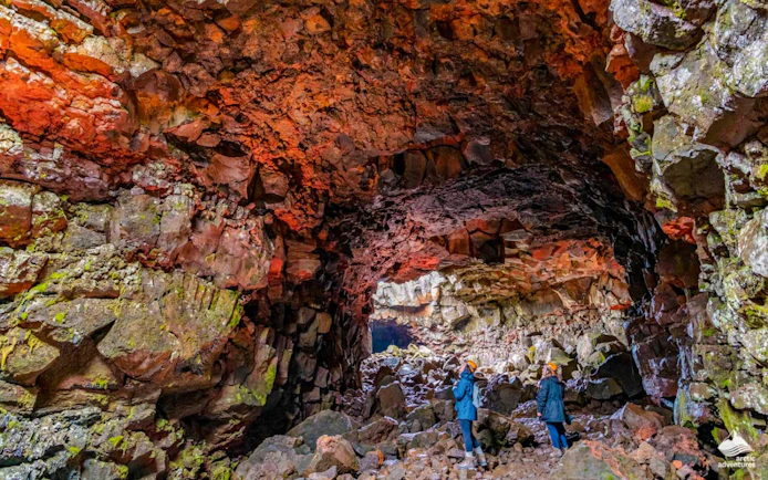 Guests exploring Raufarhólshellir Lava Tunnel's colorful rock formations.