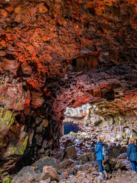 Guests exploring Raufarhólshellir Lava Tunnel's colorful rock formations.