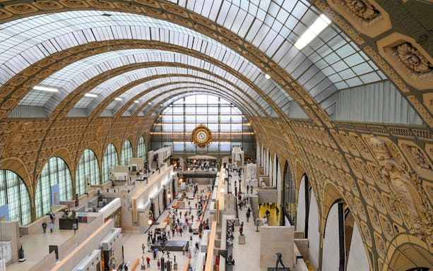 Interior view of Musée d'Orsay with sculptures and visitors, Paris day trip.