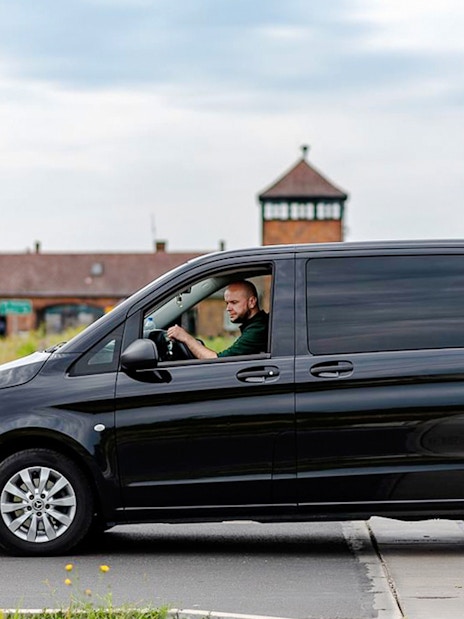 Minibus transfer to Auschwitz II with driver near entrance gate.