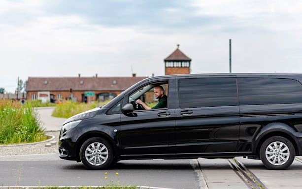 Minibus transfer to Auschwitz II with driver near entrance gate.