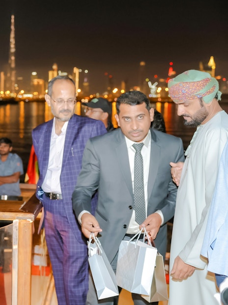 Musician playing saxophone on Dubai Canal dinner cruise with city skyline in background.