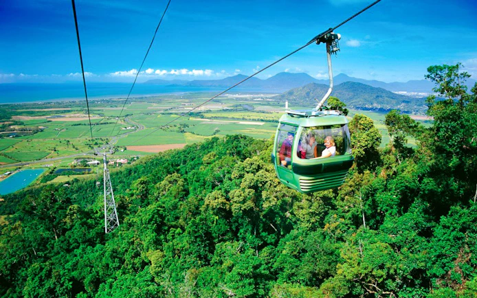 Skyrail gondola over rainforest with views of Kuranda and coastline in Australia.