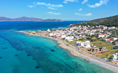 Coastal view of a Greek island near Athens with turquoise waters and a seaside village.