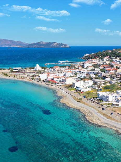 Coastal view of a Greek island near Athens with turquoise waters and a seaside village.