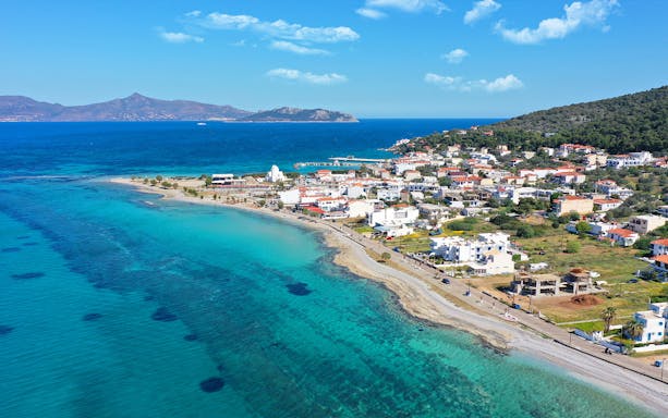 Coastal view of a Greek island near Athens with turquoise waters and a seaside village.