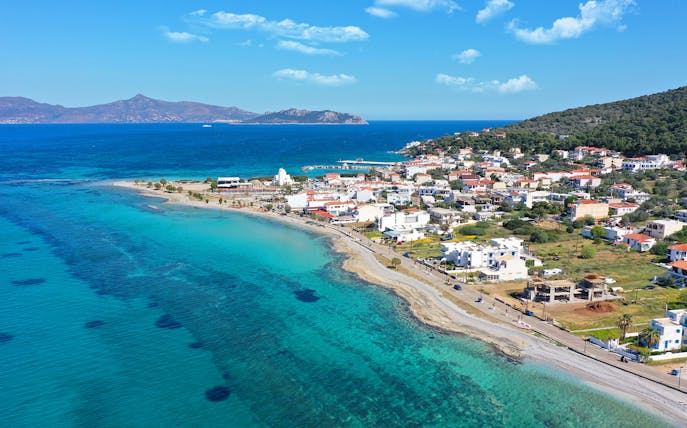 Coastal view of a Greek island near Athens with turquoise waters and a seaside village.