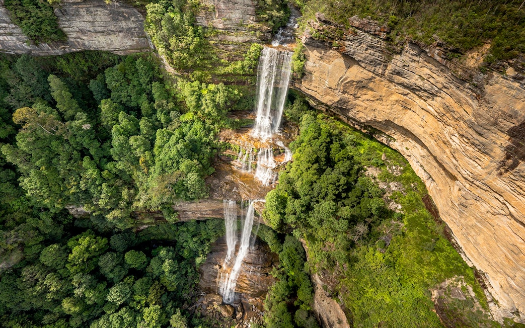 Aerial view of Katoomba Falls cascading through lush green forest, Blue Mountains, Australia.