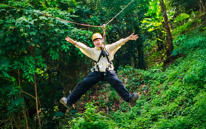 Ziplining through lush forest at Flying Hanuman, Phuket, Thailand.