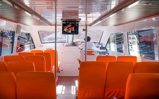 Interior of a fast boat with orange seats, traveling between Bali, Nusa Penida, Gili Islands, and Lombok.