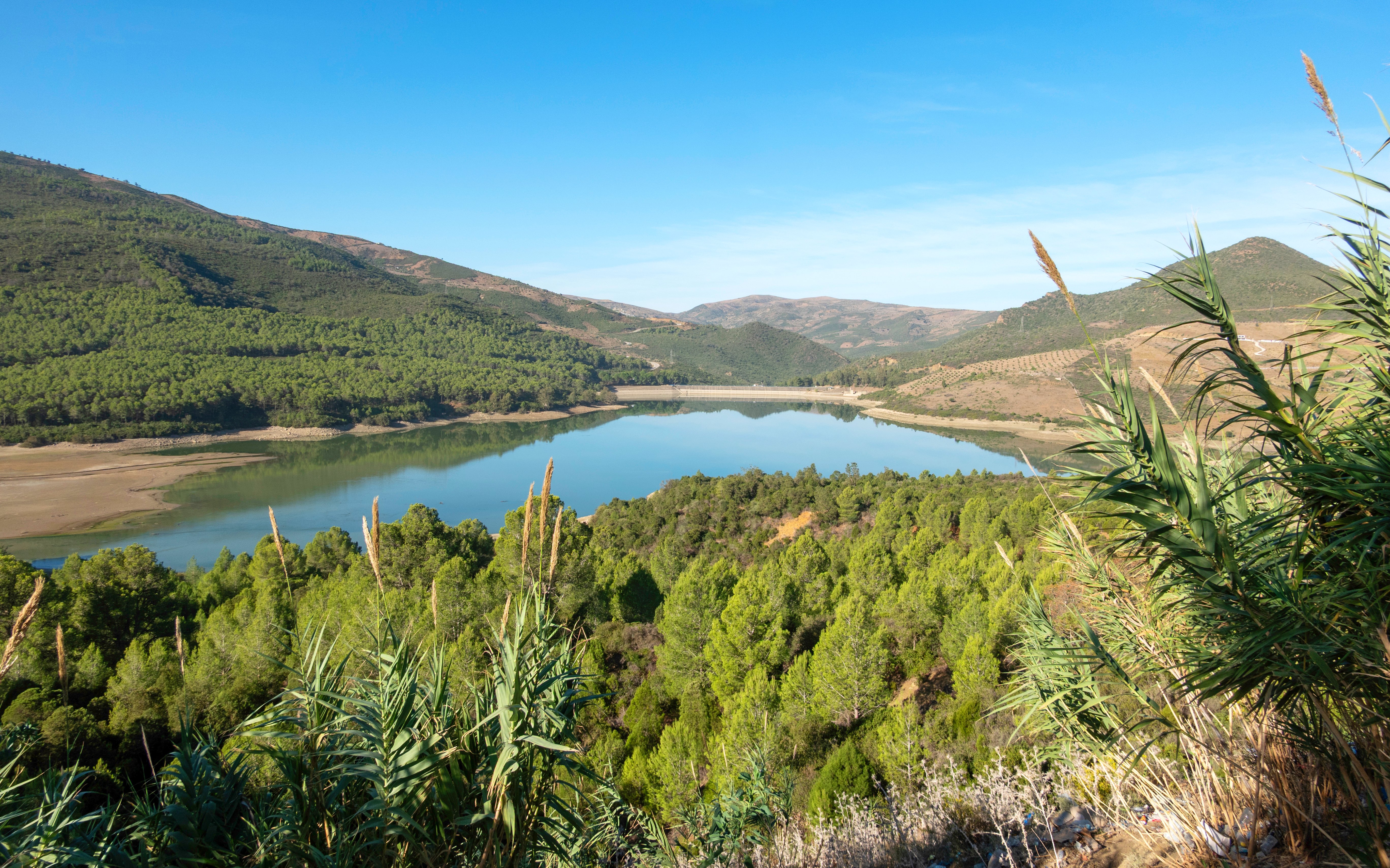 Scenic view of Lac du Barrage Sed Nakhla dam surrounded by lush hills in Zinat, Morocco.