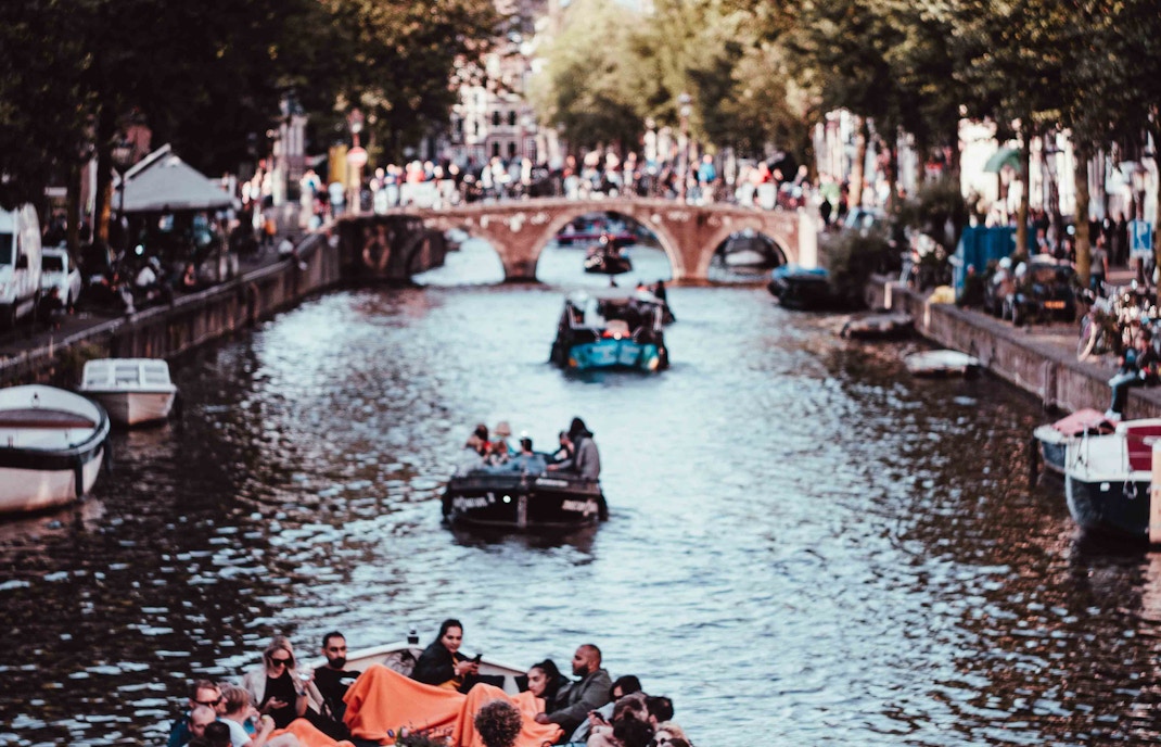 Amsterdam canal boat cruise with historic buildings and bridges in view.