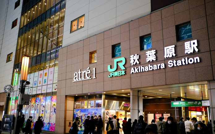 Akihabara Station entrance in Tokyo, featuring anime-themed storefronts and bustling visitors.