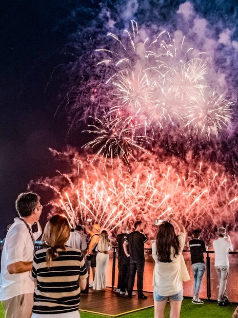 Crowd watching fireworks over Marina Bay, Singapore, celebrating the champion's victory.
