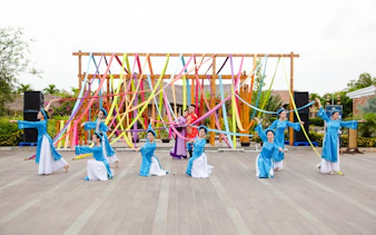 Performers in traditional attire at Hoi An Memories Show with colorful ribbons.