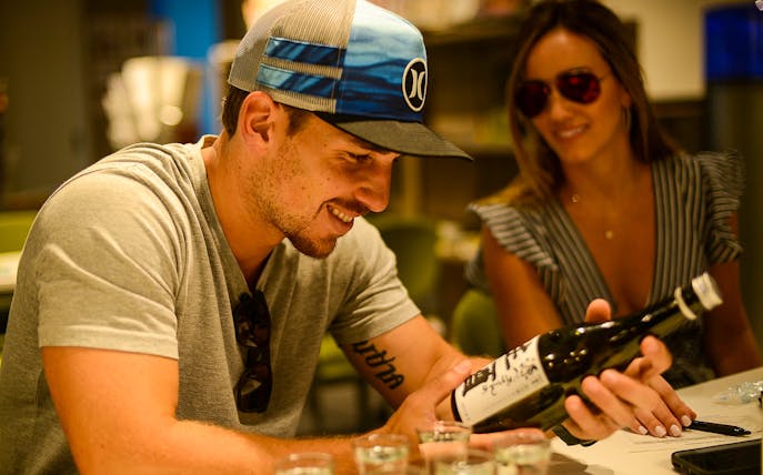 Man examining sake bottle during Kyoto sake tour experience.