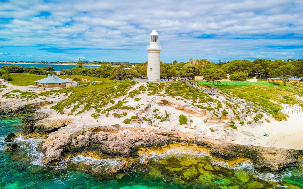 Aerial view of Bathurst Lighthouse on Rottnest Island with surrounding greenery and coastline.