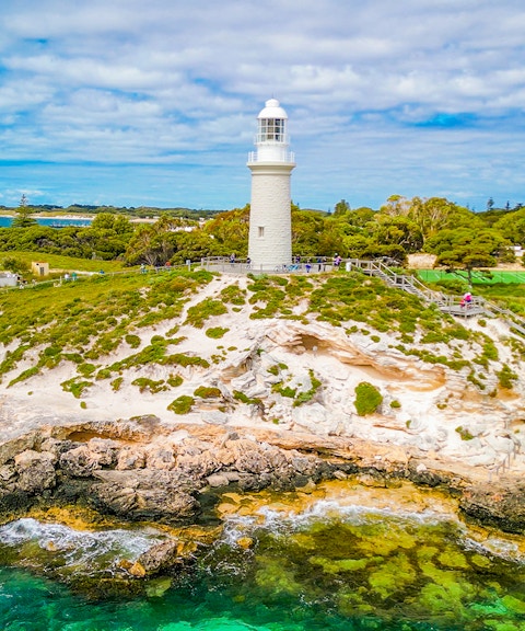 Aerial view of Bathurst Lighthouse on Rottnest Island with surrounding greenery and coastline.