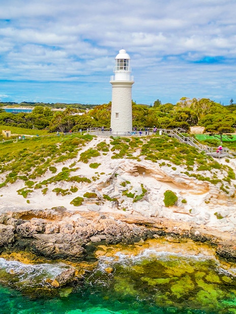 Aerial view of Bathurst Lighthouse on Rottnest Island with surrounding greenery and coastline.