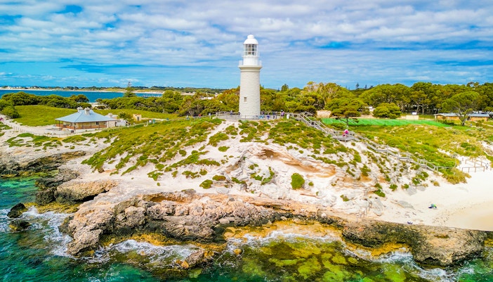 Aerial view of Bathurst Lighthouse on Rottnest Island with surrounding greenery and coastline.