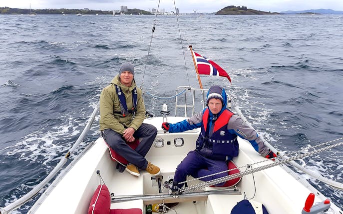 Guests sailing on Stavanger Fjord with Norwegian flag in view.