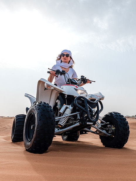 Person riding an ATV on Dubai desert safari.