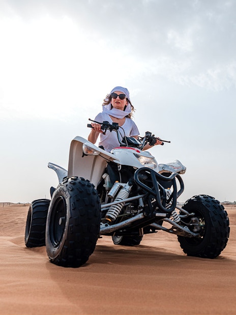Person riding an ATV on Dubai desert safari.