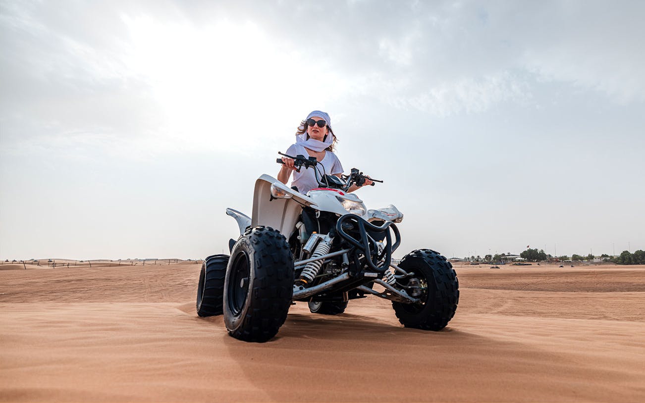 Person riding an ATV on Dubai desert safari.