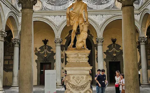 Statue in courtyard of Palazzo Medici Riccardi, Florence, with tourists on a guided walking tour.