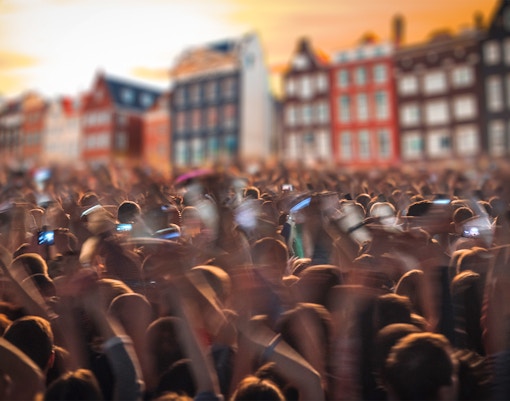 People dancing at Amsterdam Dance Event with vibrant lights and DJ in the background.