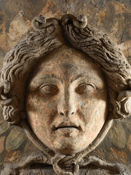 Ancient carved face detail at Ipogeo dei Cristallini, Naples.