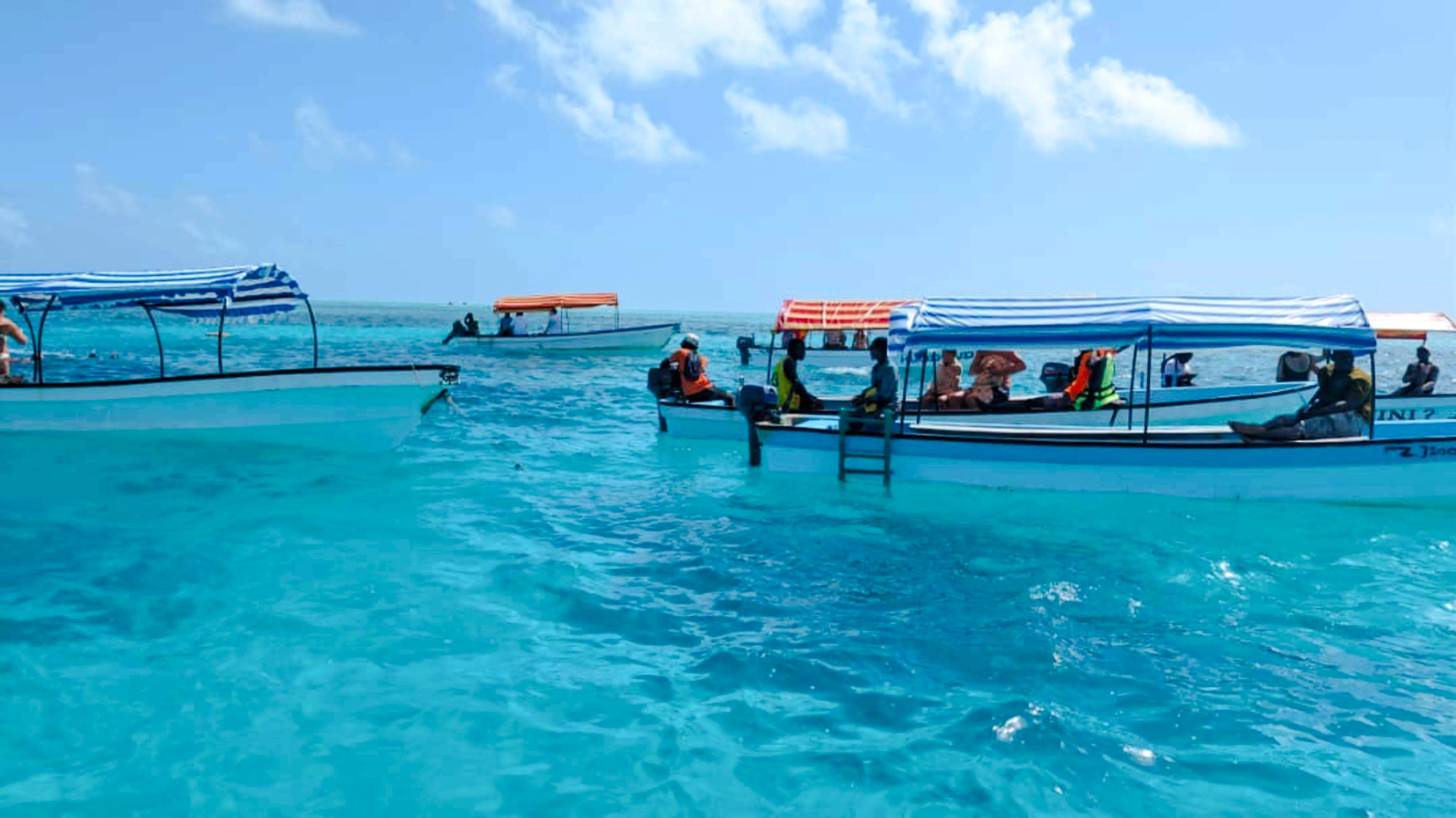 Boats with tourists on a Mnemba snorkeling tour in clear blue waters, Zanzibar.